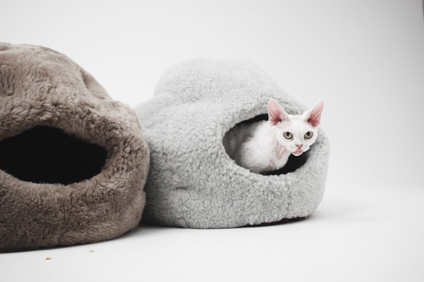 Two cat beds, one gray and one brown, with a white cat peeking out on a white background. | Natural, non‑toxic pet nest for cats and small dogs | Cozy, handmade pet furniture, natural wool and sheepskin