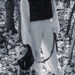 A woman standing in the woods with a dog on a leash, enjoying nature, wearing a Woolen Dog Vest in Charcoal by Mellow Pet Store.